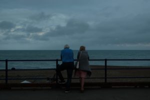 couple sitting on bench near sea during daytime